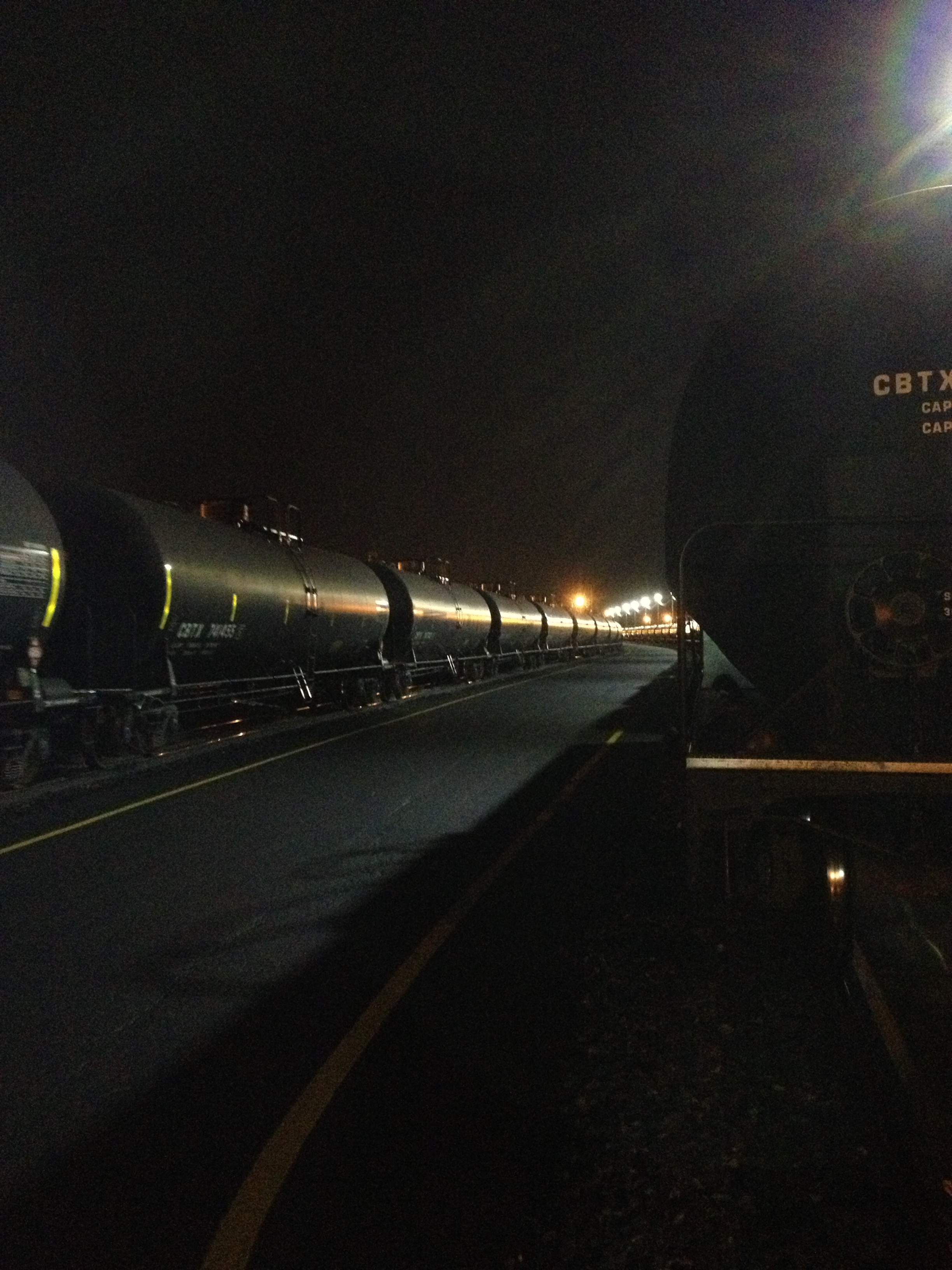Crude-by-rail unit train at the Philadelphia yard — two parallel strings of black tank cars at night under yard lights